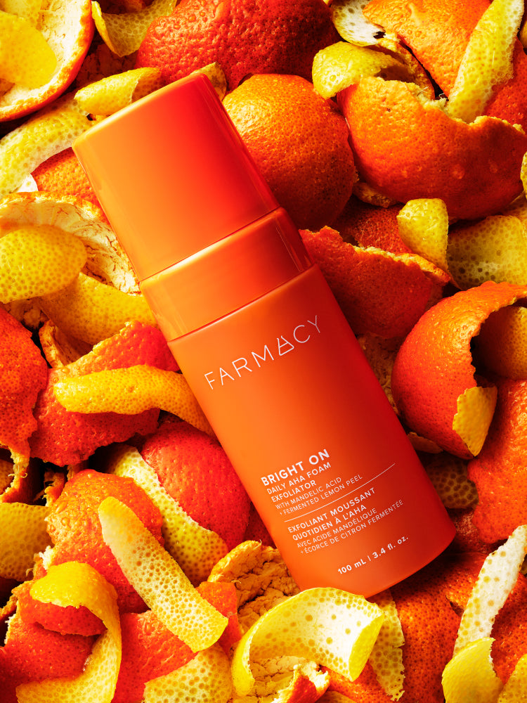 Farmacy Bright On Exfoliator on a background of orange peels