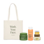 Farmacy Ultimate Best Seller Kit featuring Green Clean 100 mL, Brighten Up TXA Toner 120 mL, Honey Halo Moisturizer 50 mL, Honey Vanilla Lip Smoothie 10 g, and an off-white tote bag with the words ''WASH YOUR FACE'' written in dark green and the FARMACY logo, on a white background.