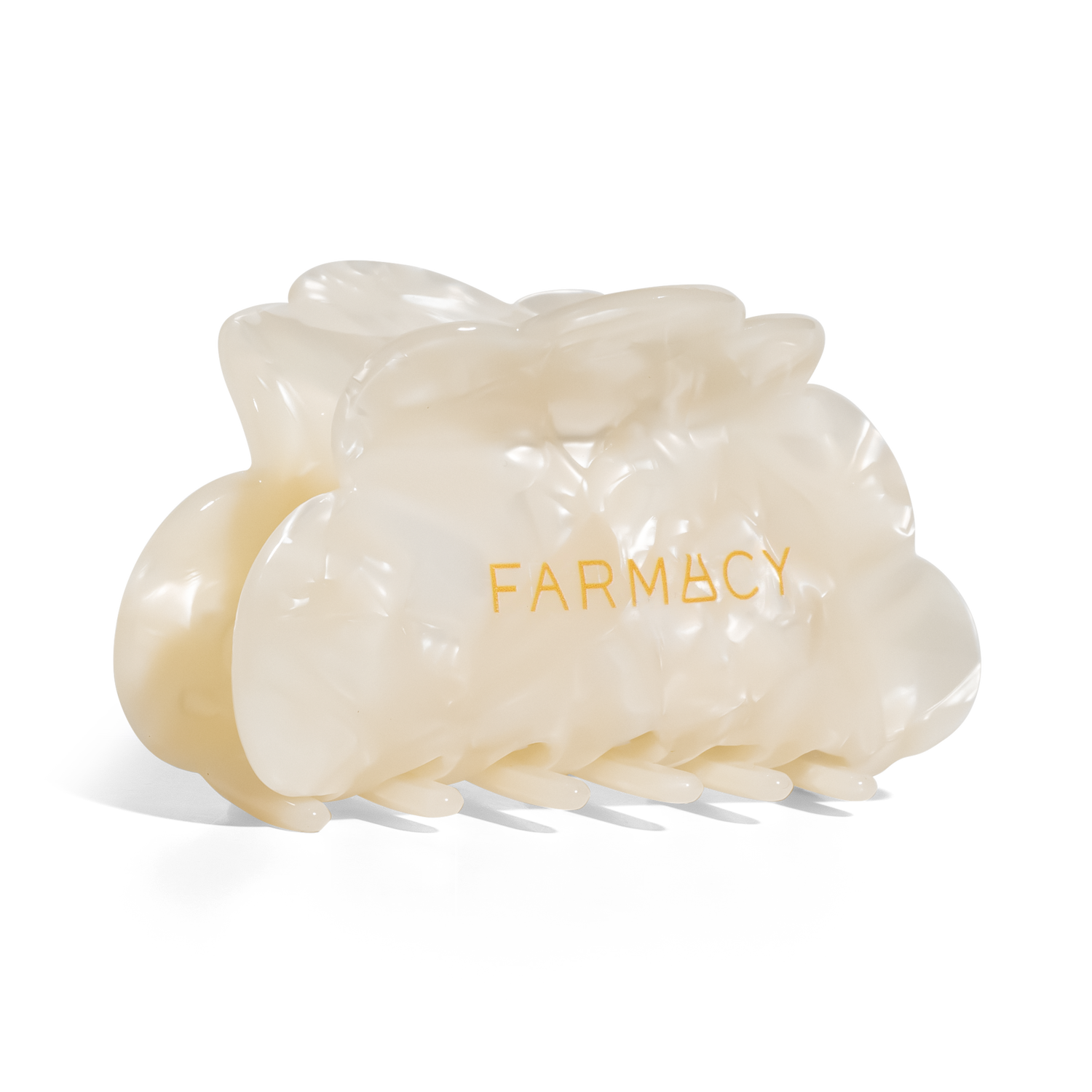 An off-white translucent claw hair clip with the brand name 'FARMACY' printed in gold on the front, set against a plain white background