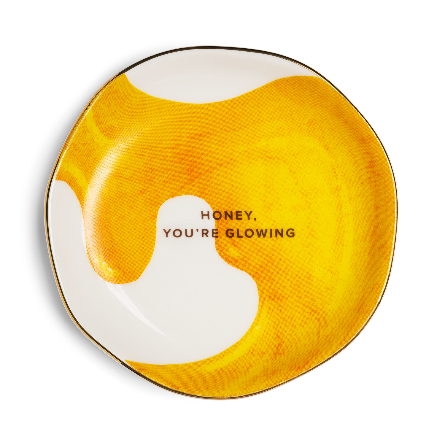 A round ceramic plate with an organic wavy outline, featuring a yellow and white marbled honey-like pattern with the text 'HONEY, YOU'RE GLOWING' printed in black in the center, set against a plain white background