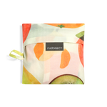 A folded reusable Farmacy x Baggu reusable shopping bag with a watercolor-style fruit print featuring oranges, apples, pears, and kiwi slices on a white background