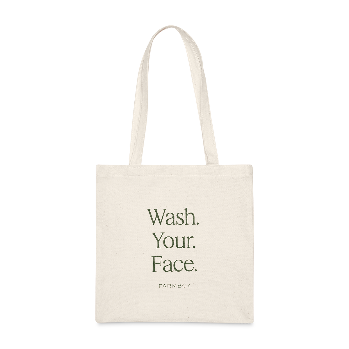 An off-white canvas tote bag with long handles, featuring the text 'Wash Your Face'' with the Farmacy logo on a white background