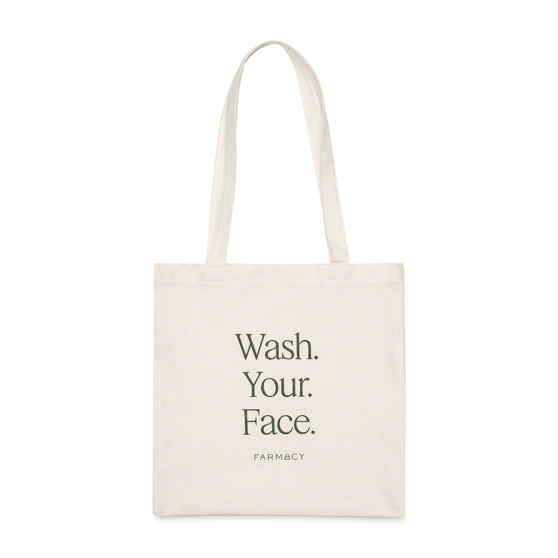 An off-white canvas tote bag with long handles, featuring the text 'Wash Your Face'' with the Farmacy logo on a white background